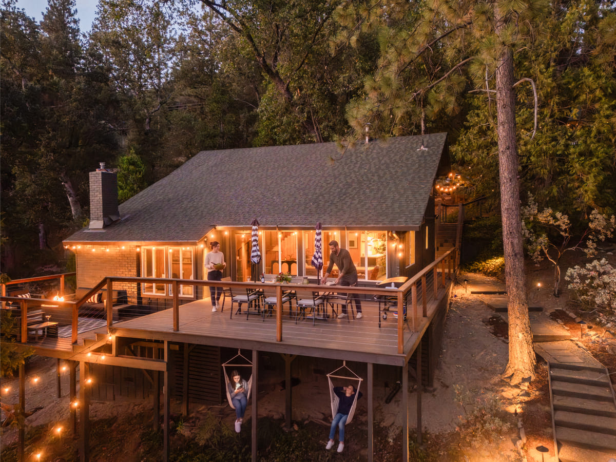The cabin at twilight, guests on the deck and in the hanging chairs
